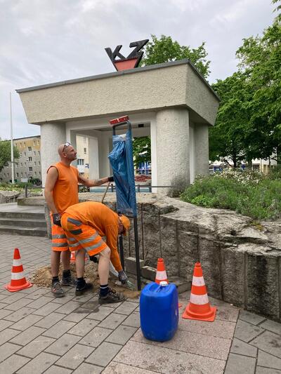 Bild vergrößern: Daniel Heilmann (l.) und Maurice Zimmermann bauen am KZ-Denkmal am Postplatz in Hennigsdorf die neue Beschilderung mit Informationen auf